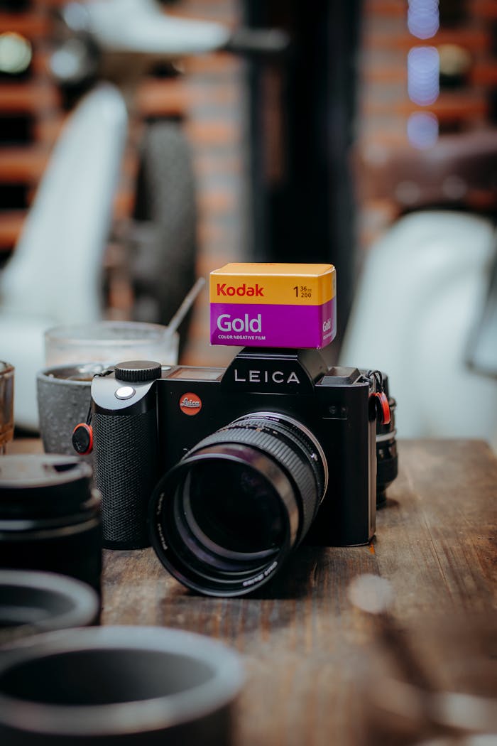 services-03 Classic Leica camera and Kodak Gold film on a rustic wooden table.