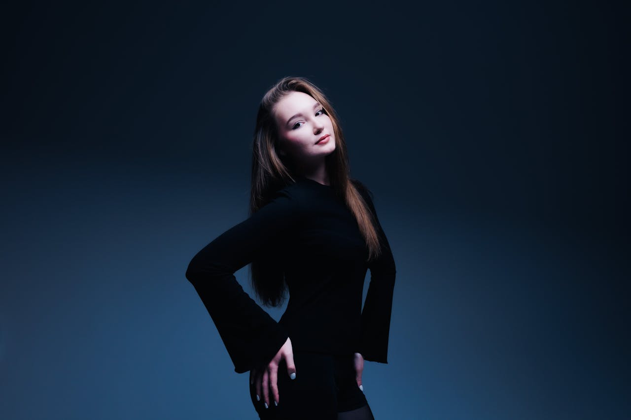services-01 Studio portrait of a confident young woman in a stylish black outfit with a blue background.